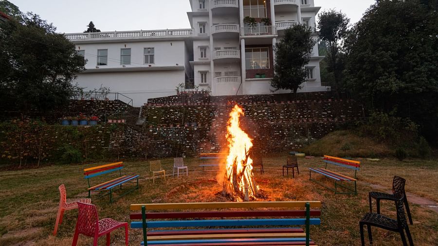 A cosy bonfire surrounded by colourful chairs and benches on the grounds of DLS Tehri Club Resort.